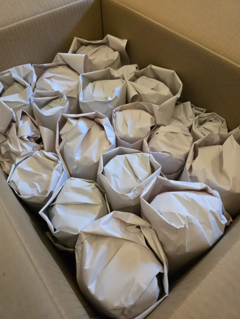 Glassware wrapped in packing paper inside a moving box