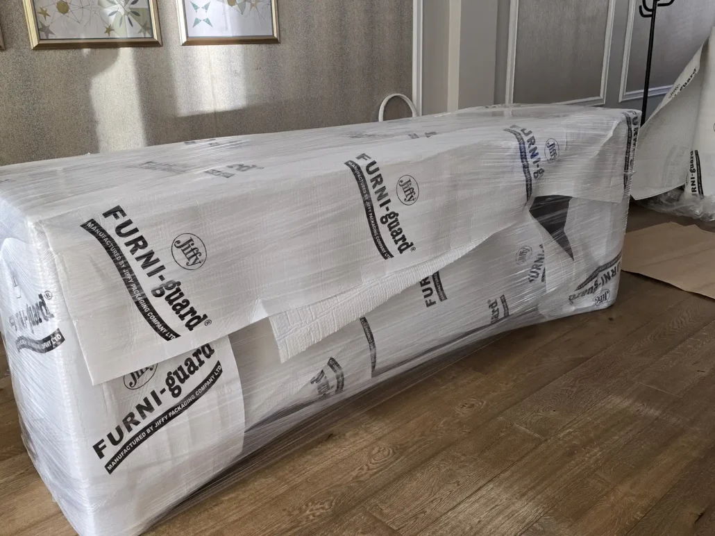 Sofa wrapped in a protective furniture cover for transport